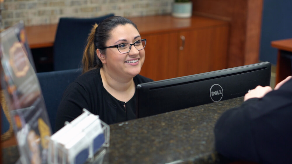 Friendly receptionist at Greater Long Island Dental in Massapequa, NY helping patient